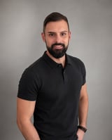 Man with dark beard wearing black polo shirt, professional headshot